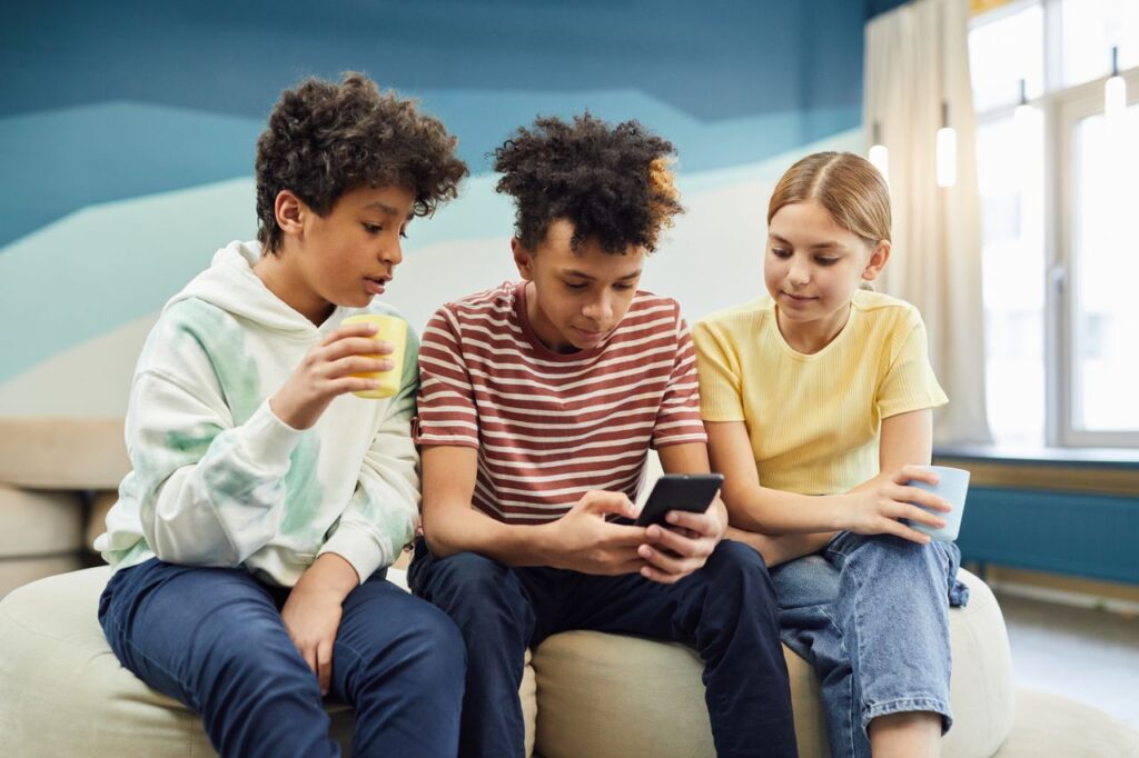 Grupo de amigos usando el móvil juntos, representando un chat grupal de WhatsApp